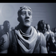 Fortnite character looks on with his mouth agape as he watches a man on screen spoofing Apple's 1984 Apple's Macintosh Commercial in Epic's #FreeFortnite campaign video.